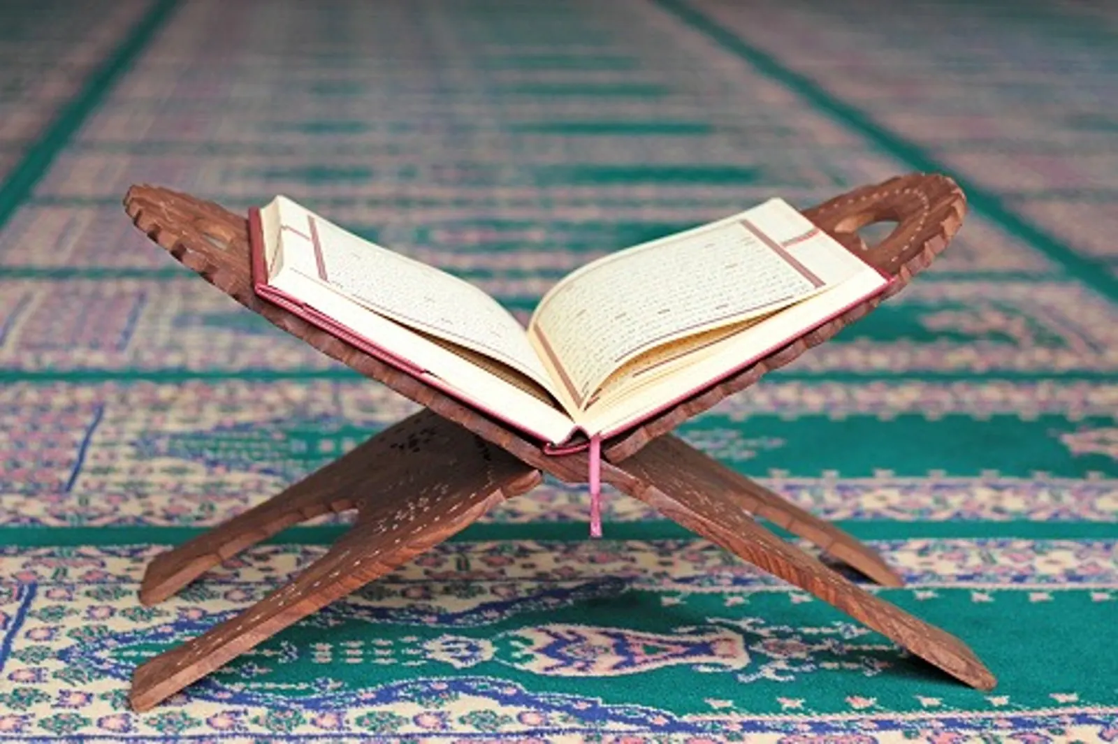 An open Quran on a carved wooden stand